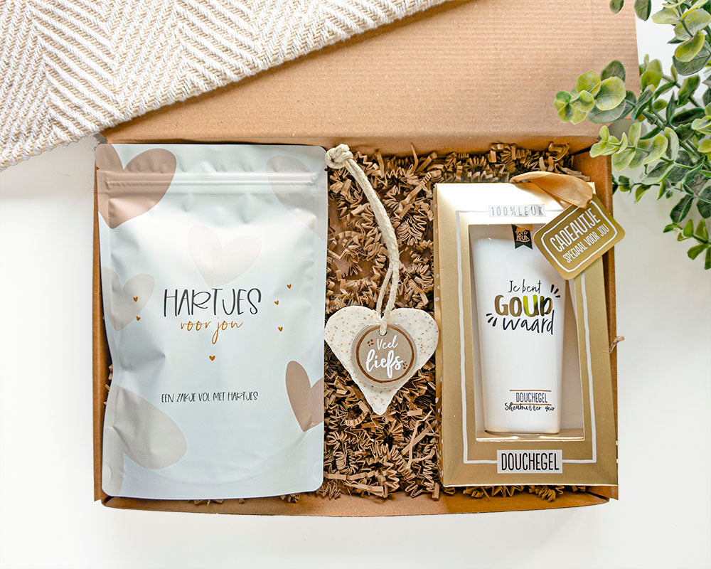 cadeaus voor haar voorzien van luxe goudfolie in een cadeaupakket. In het pakket zit een zak snoep met de tekst hartjes voor jou, een zeephart met veel liefs en een douchegel met de tekst je bent goud waard.