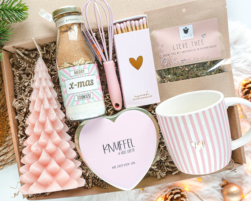Luxe kerstcadeaupakket voor haar – Zoet Kerstgeluk met mok met goud hartje, kerstkoekjesmix, thee en kaars in warme roze tinten.