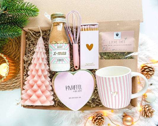 Cadeaupakket Zoet Kerstgeluk – kerstcadeau voor vrouw met mok, thee, bakfles, snoep, kaars en lucifers in roze en goud, sfeervol verpakt.
