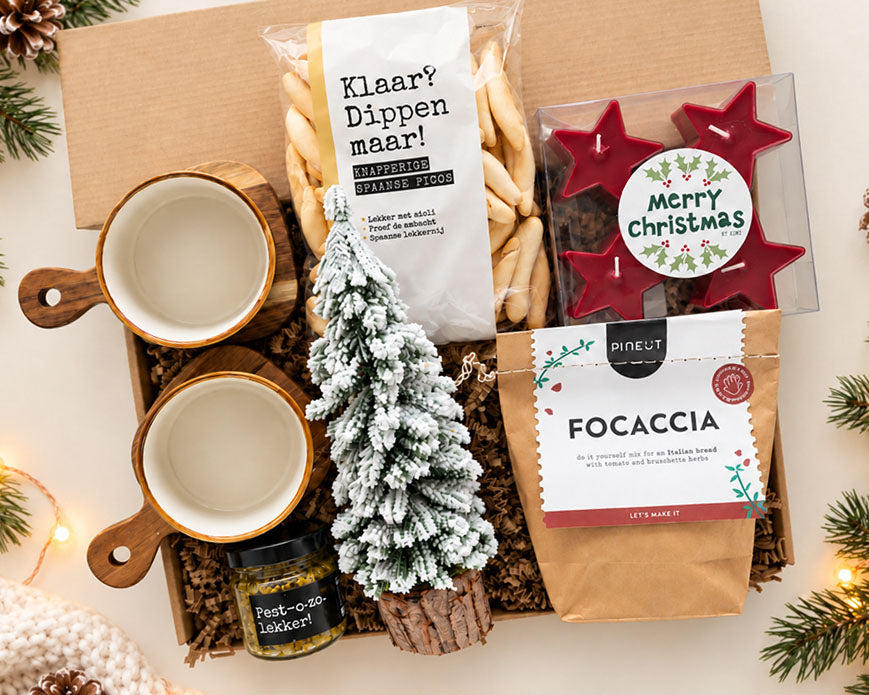 Sfeervol kerstpakket met eten, rode kerstkaarsjes, decoratieve kerstboom en serveerschaaltjes